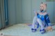 A woman in a blue and white outfit sitting on a white rug.