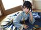 A woman in a blue kimono sitting on the floor.