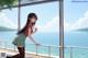 A girl in a school uniform leaning against a railing by the water.