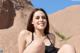 A woman in a black bathing suit sitting on a rock.