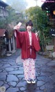 A woman in a red kimono is taking a selfie.