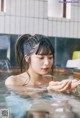 A woman in a swimming pool with her hands in the water.