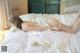 A woman laying on top of a bed in a white lingerie.