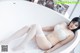 A woman in a white lingerie laying in a bathtub.