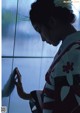 A woman in a kimono leaning against a wall.