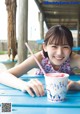 A young girl sitting at a table with a cup of ice cream.