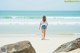 A woman walking on a beach next to the ocean.