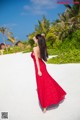 A woman in a red dress standing on a beach.